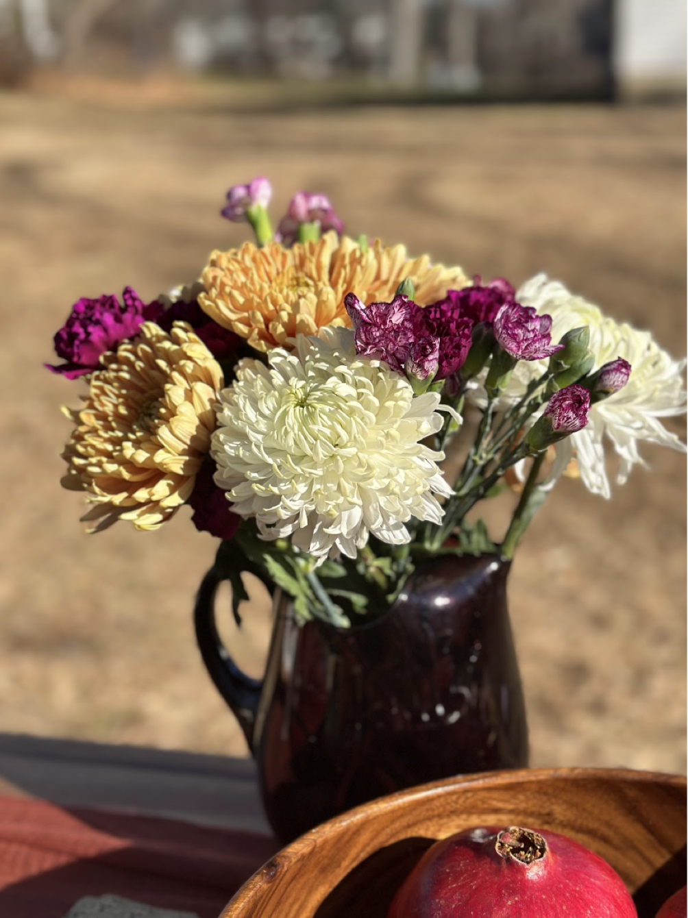 Autumn flowers in a deep burgundy pitcher